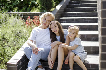 Grandmother with granddaughters sitting on steps - LLUF00452