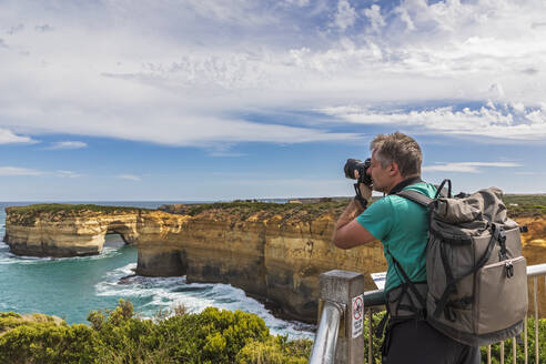 Australien, Victoria, Männlicher Tourist fotografiert natürlichen Bogen in der Loch Ard Schlucht - FOF12546