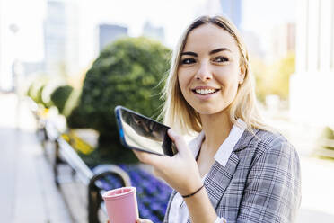 Junge Geschäftsfrau spricht durch den Lautsprecher ihres Mobiltelefons - XLGF02472