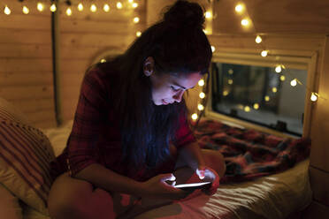 Young woman using mobile phone sitting in camper van - EGHF00311