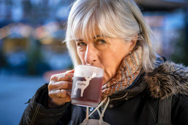 Ältere Frau trinkt Glühwein im Winter - FRF00949