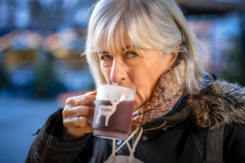 Senior woman drinking mulled wine in winter - FRF00949
