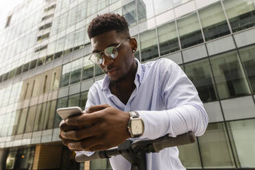 Junger Mann mit Mobiltelefon vor einem Gebäude - VYF00861