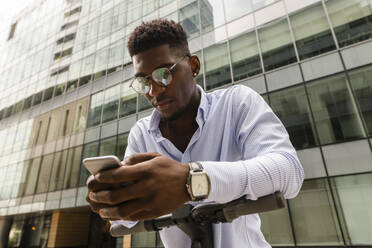 Young man using mobile phone in front of building - VYF00861