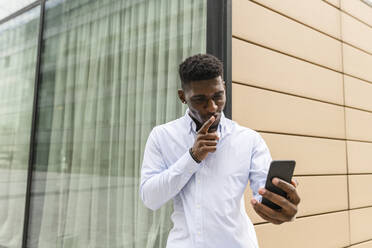 Junger Mann mit Finger auf den Lippen während eines Videogesprächs mit einem Smartphone - VYF00894