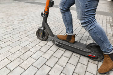 Man riding electric push scooter on footpath - VYF00897