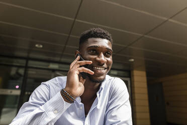 Smiling young man talking on mobile phone - VYF00899