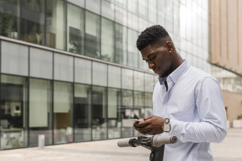 Mann, der auf dem Gehweg mit seinem Mobiltelefon SMS schreibt - VYF00905