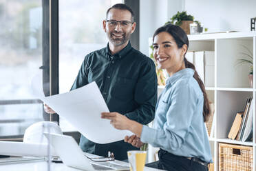 Lächelnde Architekten mit Grundriss im Büro - JSRF01770