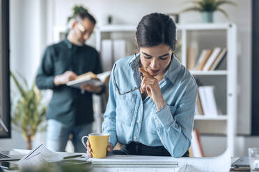 Architect looking at blueprint on desk in small office - JSRF01781