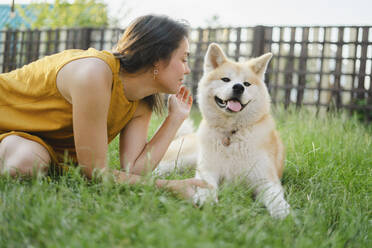 Frau kommuniziert mit Akita-Hund im Gras - SEAF00310