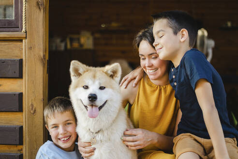 Lächelnde Söhne mit Mutter und Akita-Hund vor dem Haus - SEAF00327