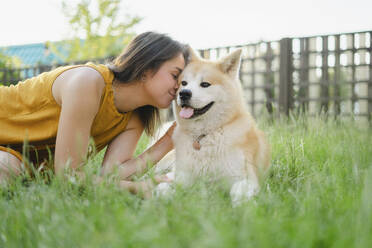 Frau küsst ihren Akita-Hund im Gras - SEAF00334