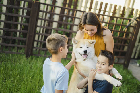 Glückliche Familie spielt mit Akita-Hund im Gras - SEAF00341