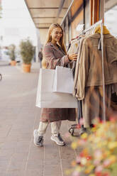 Frau kauft Kleidung ein, die auf einem Gestell vor einem Geschäft hängt - DAWF02388
