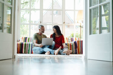 Heterosexual couple with laptop sitting at home - JOSEF06362