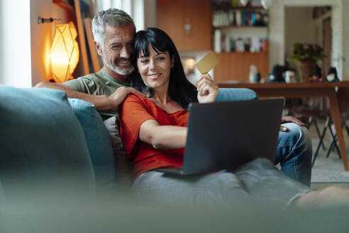 Lächelndes Paar beim Online-Shopping am Laptop zu Hause - JOSEF06370