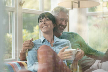 Happy woman with coffee cup by man seen through glass - JOSEF06373