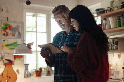 Heterosexual couple using digital tablet at home - JOSEF06375