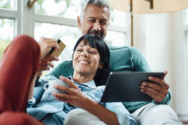 Happy couple with credit card doing online shopping on Tablet PC - JOSEF06379