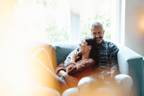Glückliches heterosexuelles Paar sitzt auf dem Sofa im Wohnzimmer - JOSEF06414