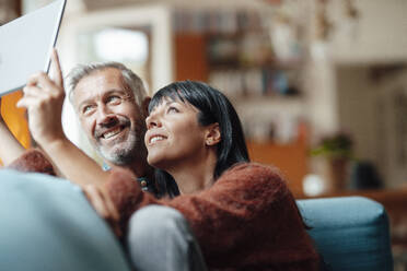 Smiling couple using tablet PC at home - JOSEF06441