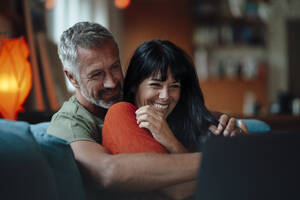 Happy mature couple using tablet PC in living room - JOSEF06457