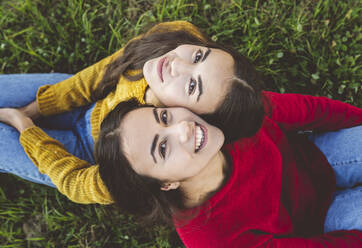 Smiling twin sister sitting on grass - JCCMF05005