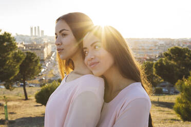 Smiling woman embracing thoughtful sister at sunset - JCCMF05010