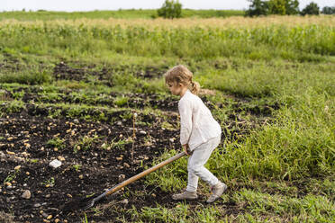 Mädchen mit Mistgabel auf einem landwirtschaftlichen Feld - DIGF17394