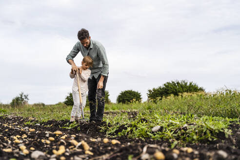 Tochter hilft Vater bei der Arbeit auf einem landwirtschaftlichen Feld - DIGF17396