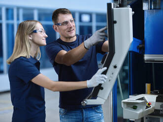 Techniker mit Schutzbrillen diskutieren über eine CNC-Maschine - CVF01769