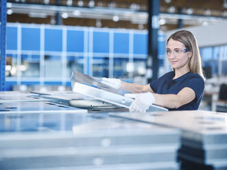 Young technician with protective eyewear and gloves holding metal frame - CVF01778