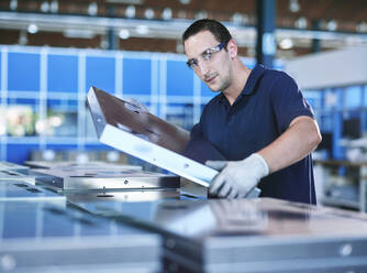 Arbeiter mit Schutzbrille bei der Prüfung eines Metallrahmens in der Industrie - CVF01780