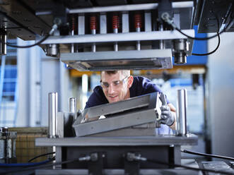 Techniker beim Einstellen von Metallrahmen in einer Maschine im Werk - CVF01785