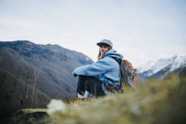 Lächelnder Backpacker mit Mütze und Rucksack im Urlaub - OMIF00341