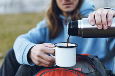 Man pouring coffee from insulated drink container - OMIF00347