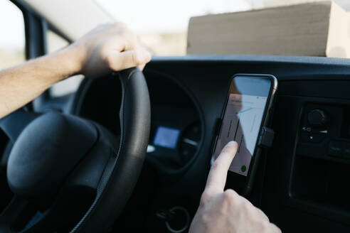 Mann benutzt GPS auf seinem Smartphone, während er einen Lieferwagen fährt - JRFF05214
