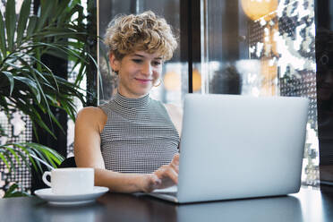 Junge Geschäftsfrau arbeitet an einem Laptop in einem Café - PNAF02739