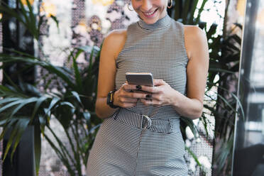 Lächelnde Frau mit Mobiltelefon in einem Café - PNAF02759