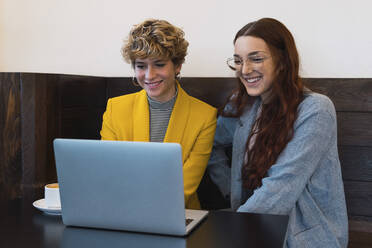 Smiling business colleagues using laptop in coffee shop - PNAF02763