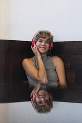 Lächelnde Frau hört Musik über Kopfhörer in einem Café - PNAF02768