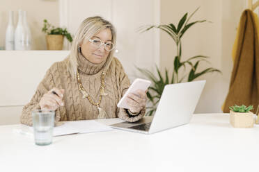 Geschäftsfrau mit Rollkragenpullover bei der Arbeit am Smartphone im Büro - JCZF00903