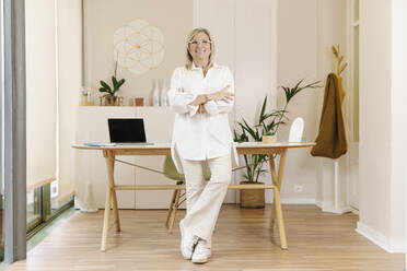 Smiling businesswoman standing with arms crossed in office - JCZF00912