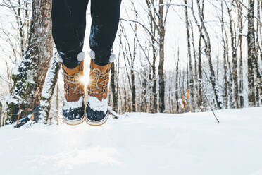 Mann mit Stiefeln springt auf Schnee im Wald - OMIF00368