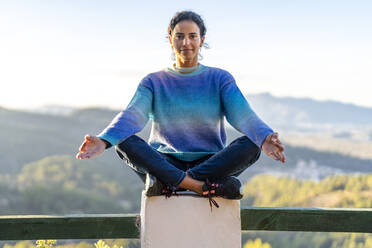 Frau beim Yoga auf dem Geländer sitzend - DLTSF02577