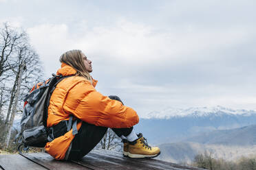 Nachdenklicher Mann mit Rucksack im Winterurlaub - OMIF00400