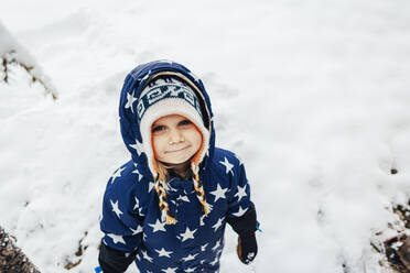 Nettes Mädchen trägt warme Kleidung mit Sternformen auf Schnee - OMIF00407