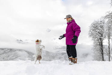 Man and dog playing with snow - OMIF00410