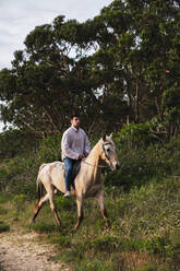 Young man riding horse at sunset - RSGF00795